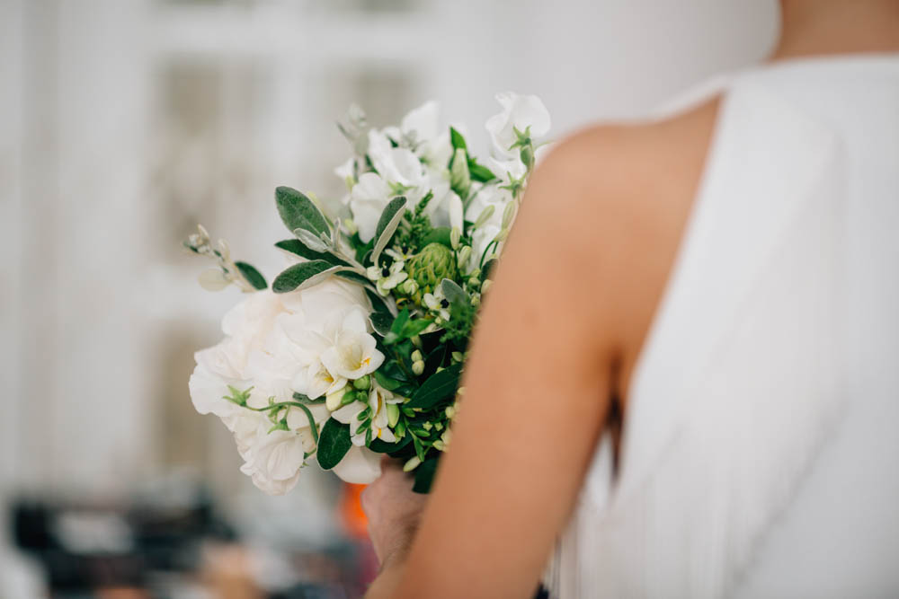 captured bride's shoulder holding bouquet of flowers